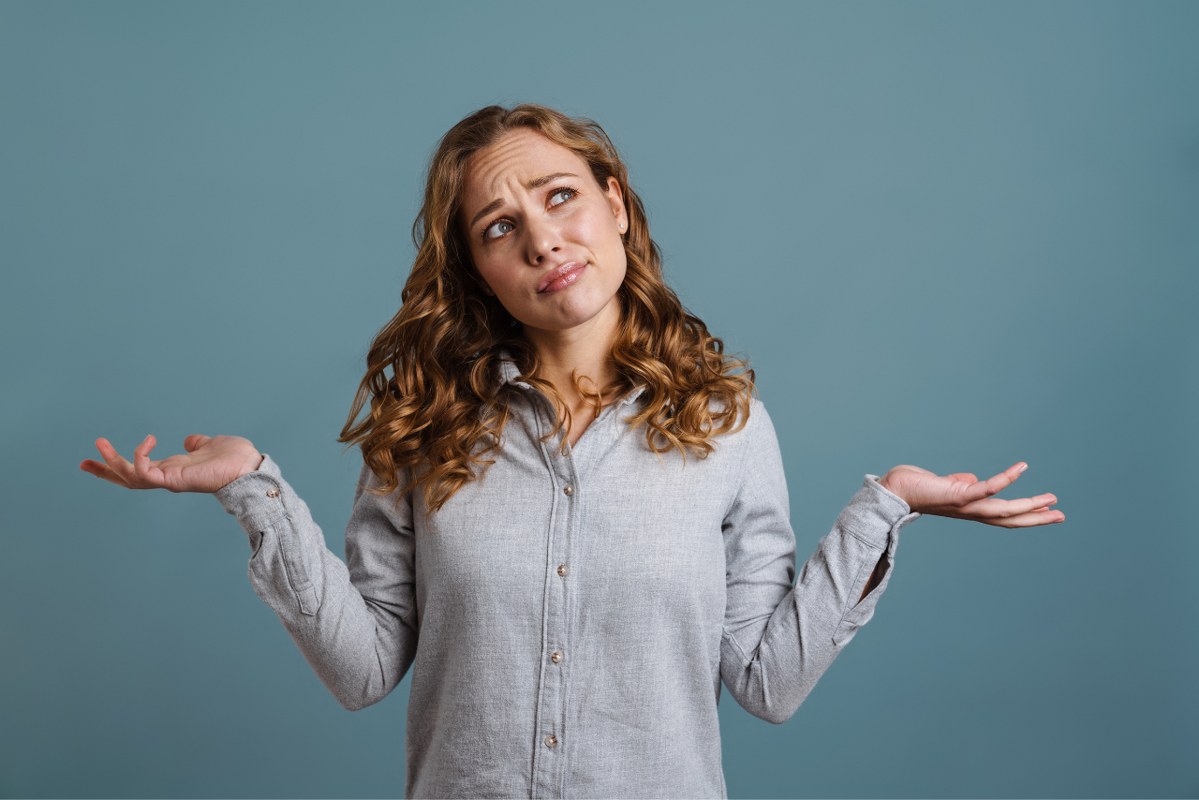 Portrait of a Pretty Confused Woman Shrugging Shoulders.