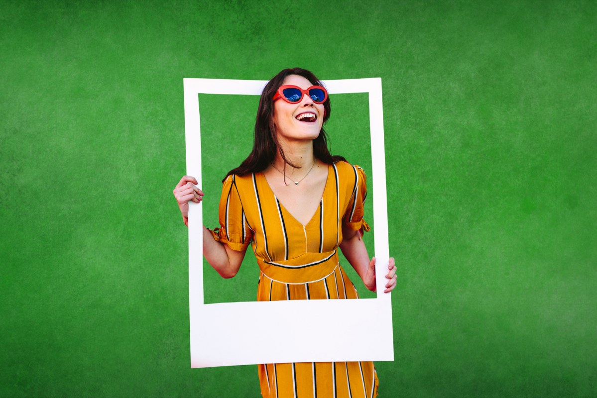 Stylish Woman with Large Photo Frame with green background.