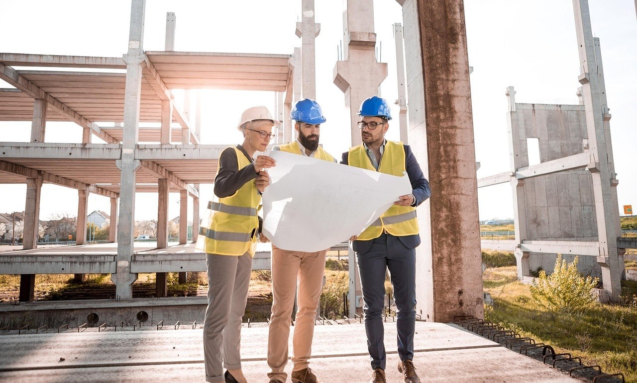 Three construction managers at work looking at a construction design.
