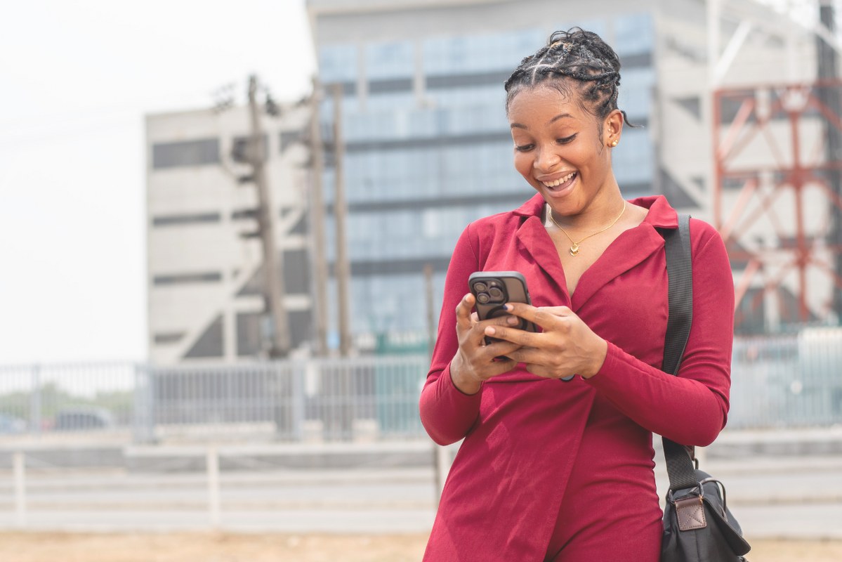 Woman checking phone and smiles at what she sees.