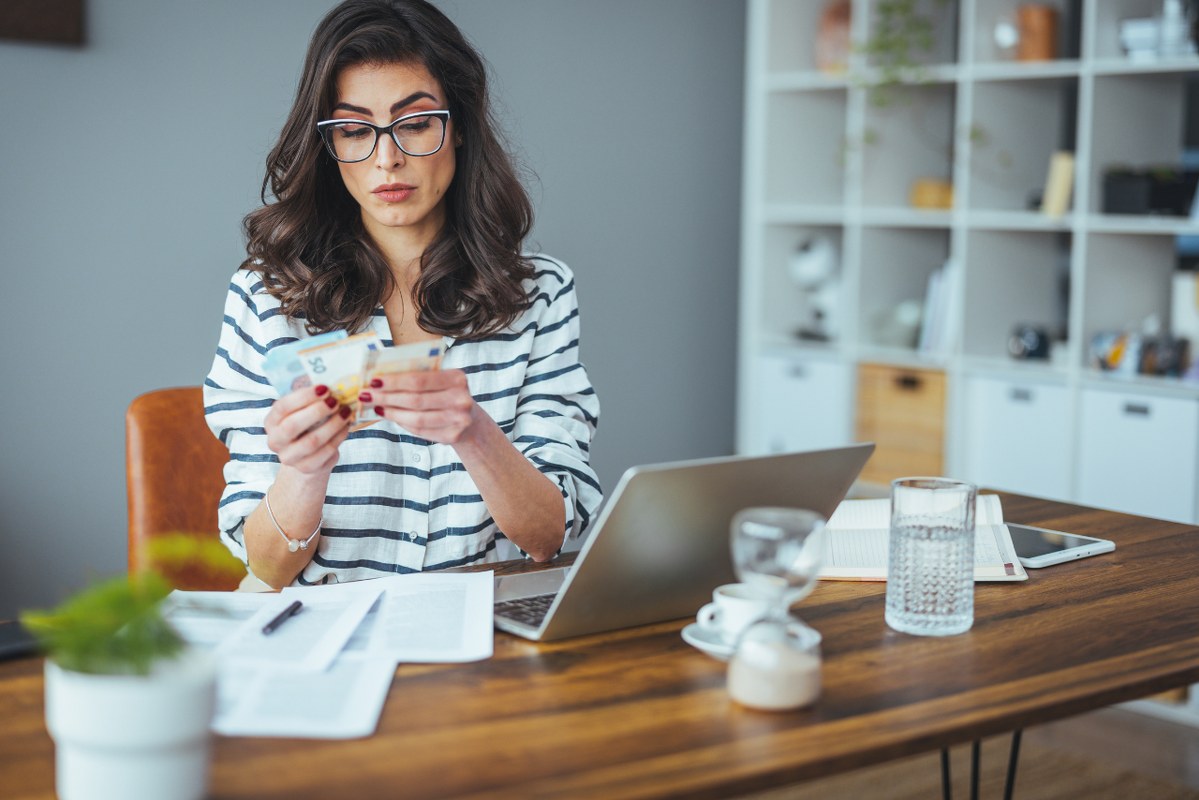 Woman counting money to pay off debt.