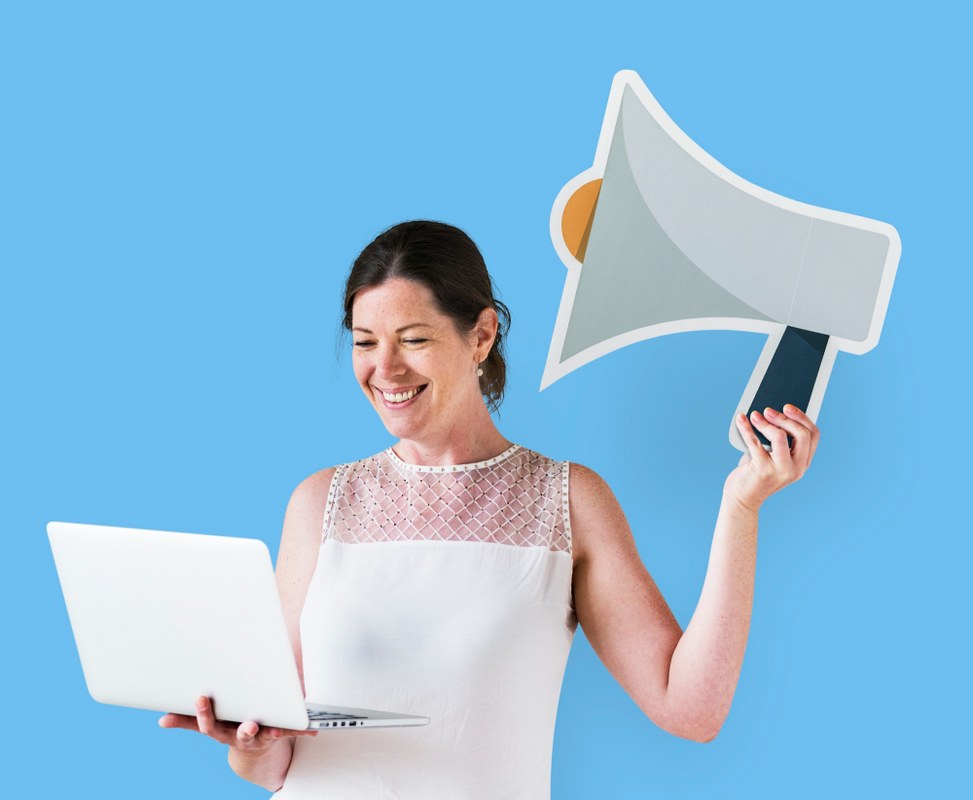 Woman holding a megaphone icon and using a laptop.