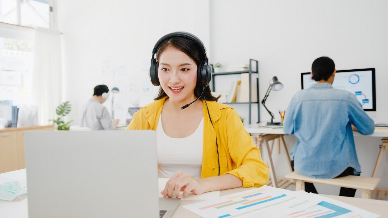 Woman is wearing headphones in front of a laptop.