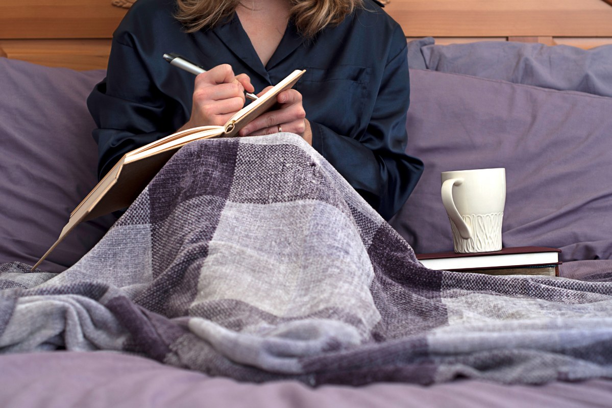 Woman journaling in bed.