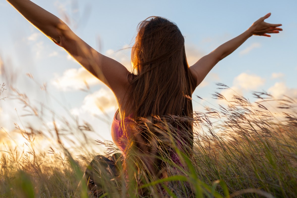Woman open arms on field.