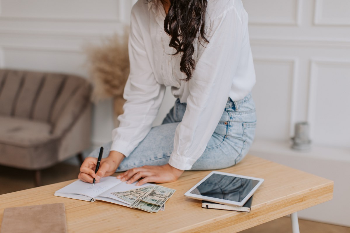 Woman sitting on table top and calculating.