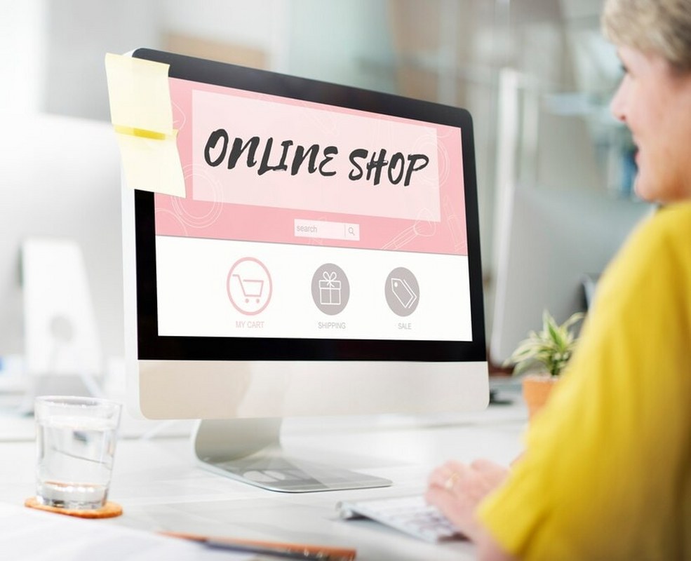 Woman using computer displaying online shop.