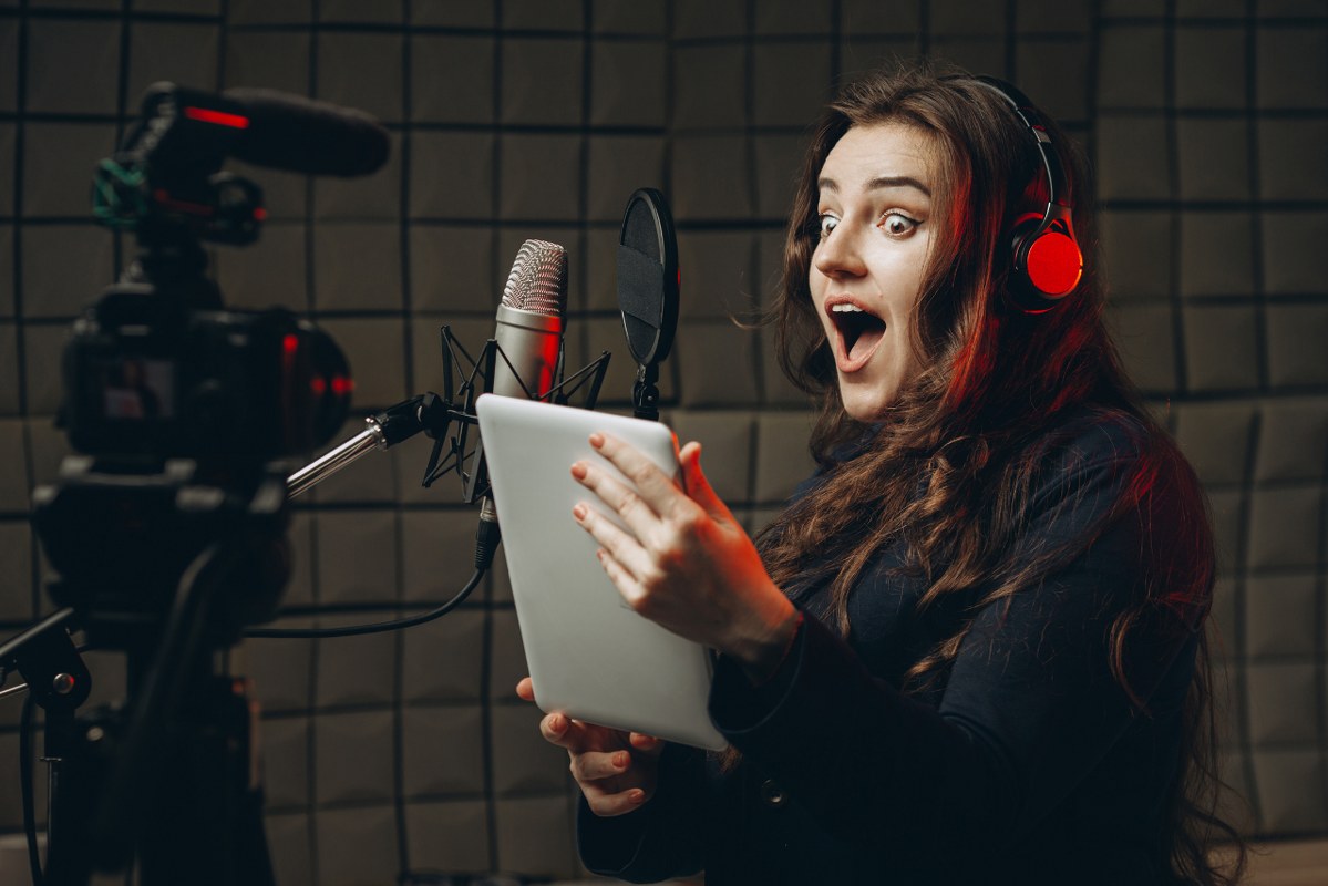 Young girl portraying a character with microphone and headphones in recording studio. 