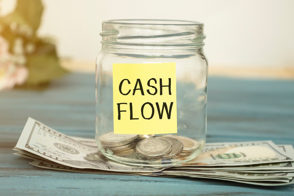 Cash flow text on a glass jar with little money.