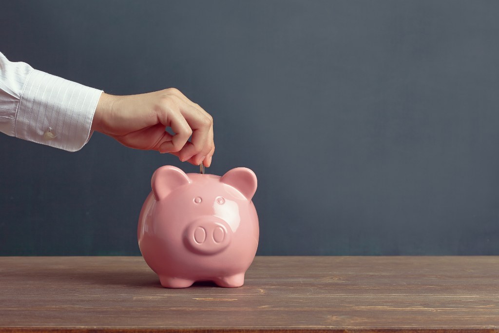 Dropping money on piggybank to save.