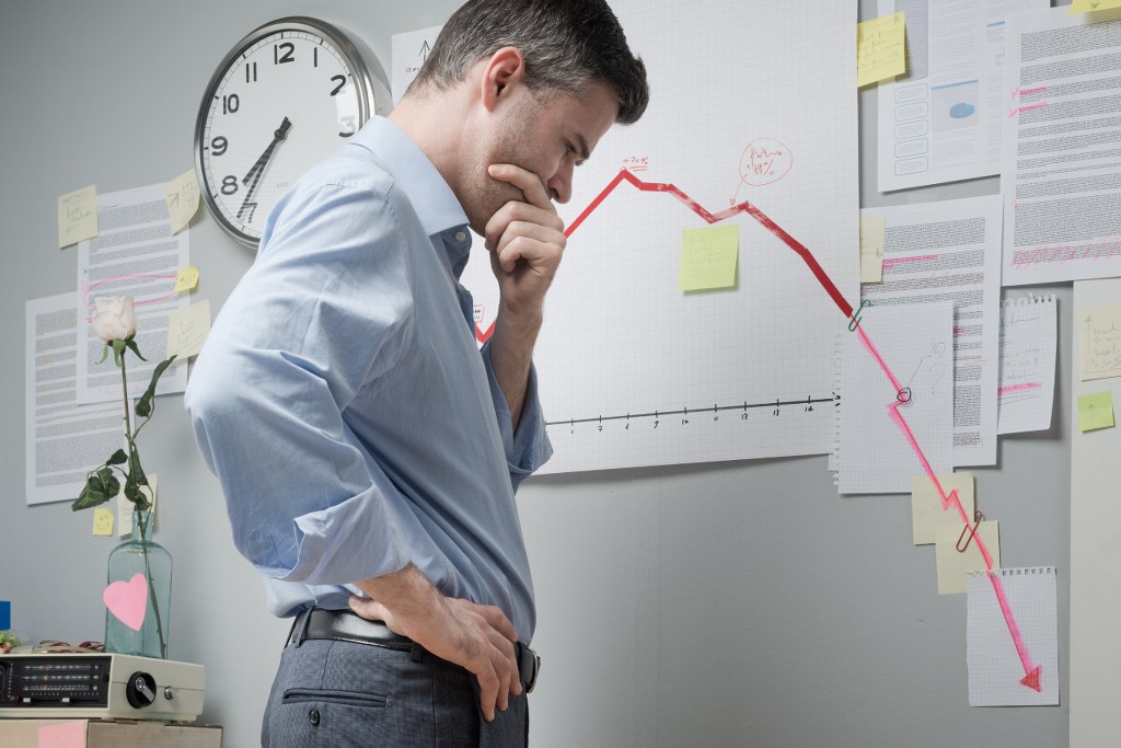 Frustrated businessman looking at downward graph.