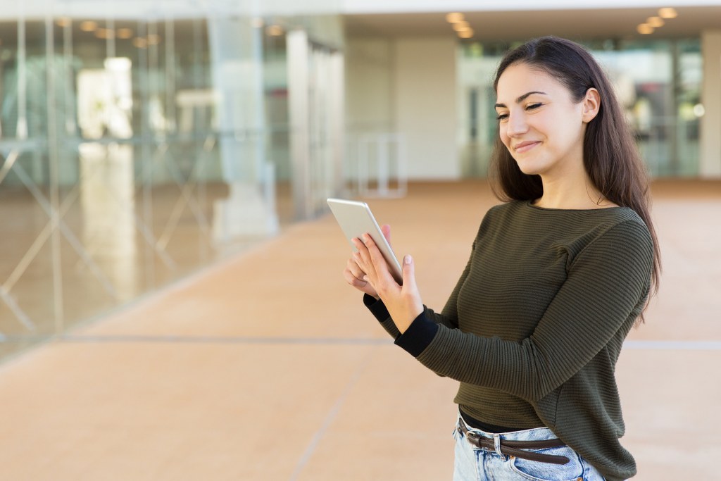 Happy satisfied female checking message on tablet.