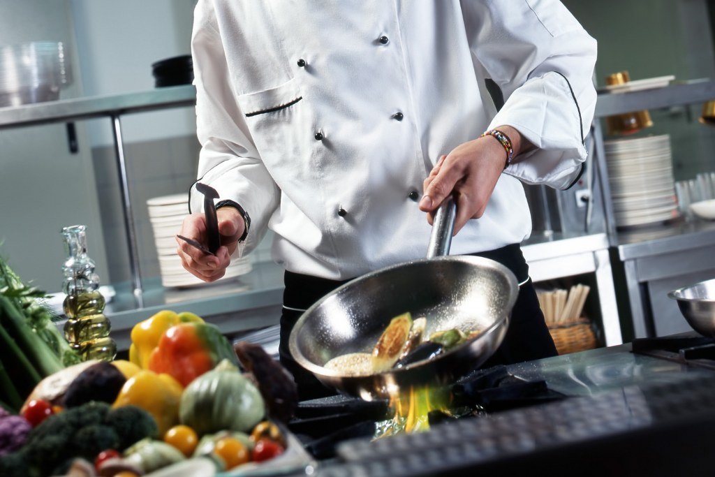 Medium-shot of a professional chef in a bustling restaurant kitchen.