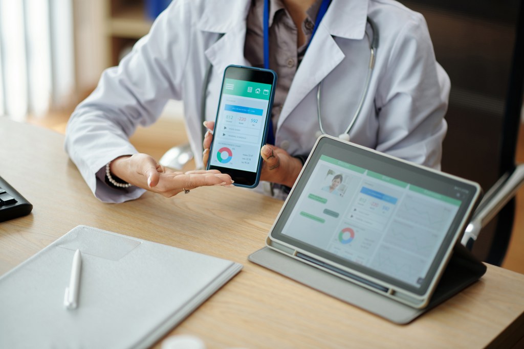 Physician presenting app on tablet and phone.