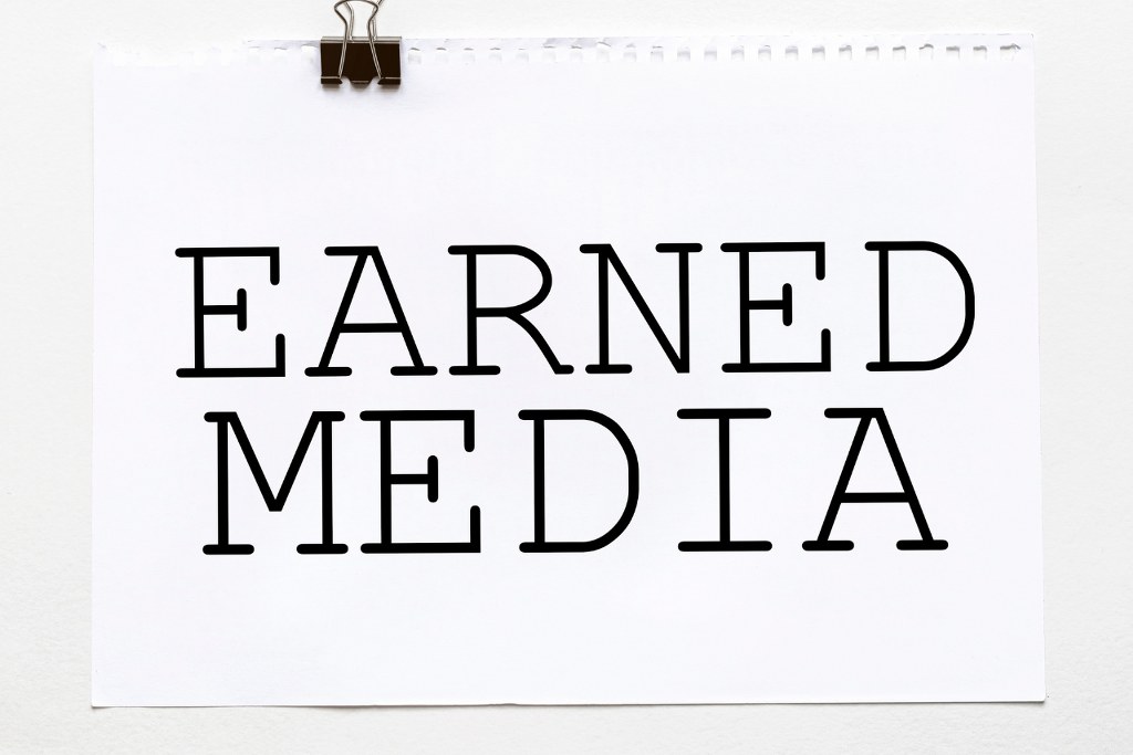 White paper with text Earned Media on a white background with stationery.