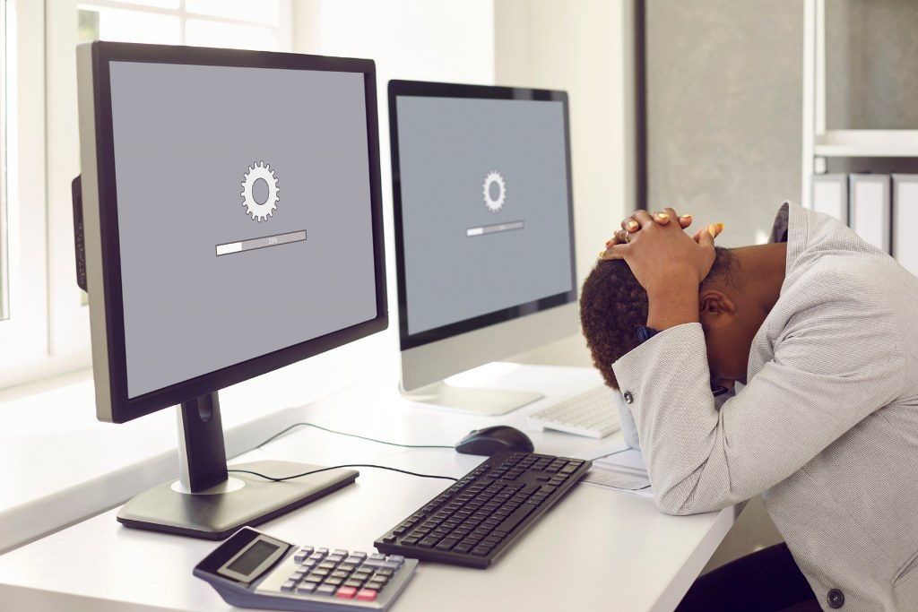 Woman Sitting in Front of Office Computers and Waiting for slow page to load.