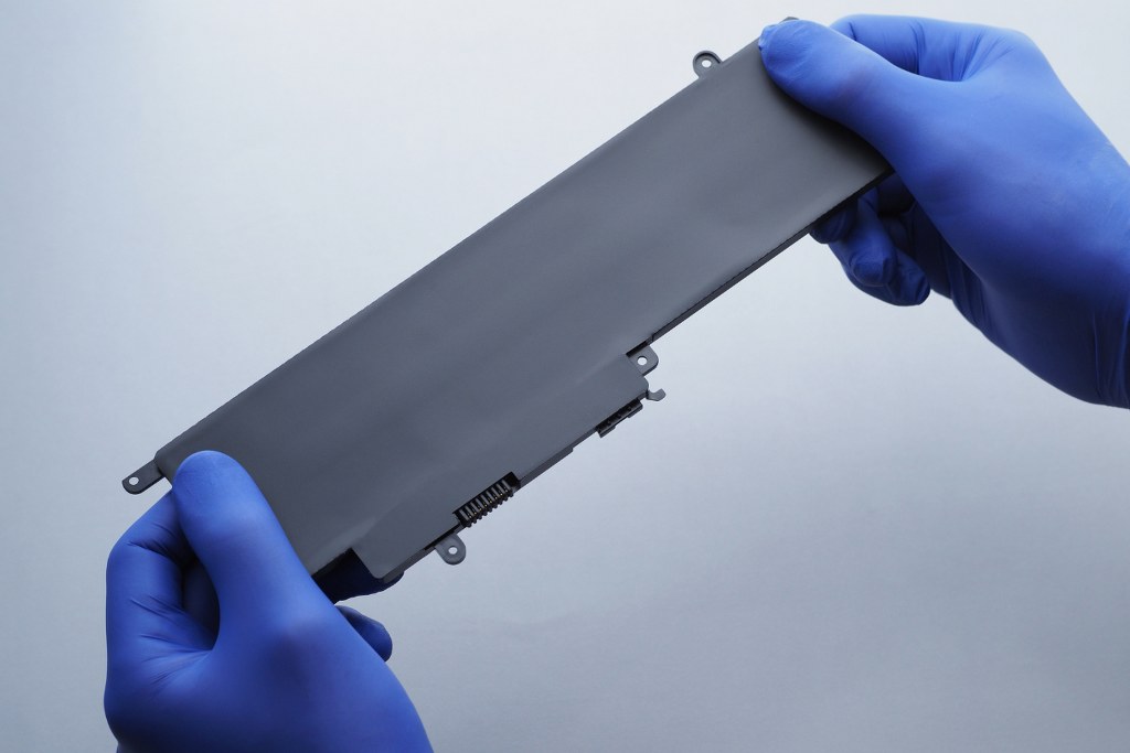 Close-up hands holding laptop battery.