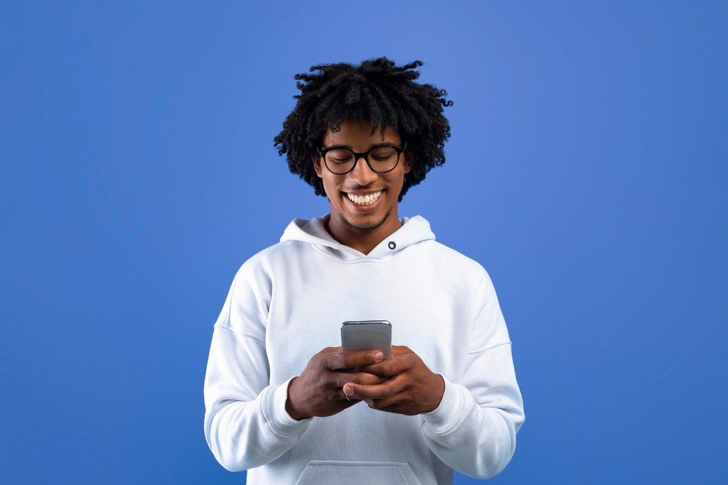 Happy Teenager Looking at Mobile Phone Screen.