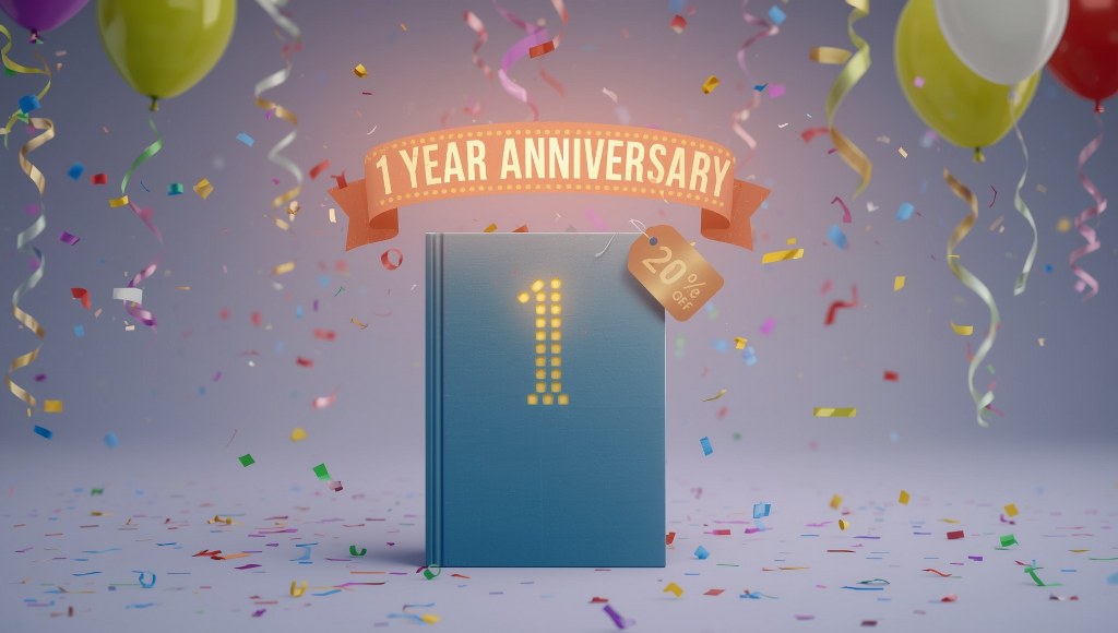 A book standing upright with a glowing 1 Year Anniversary banner above it.