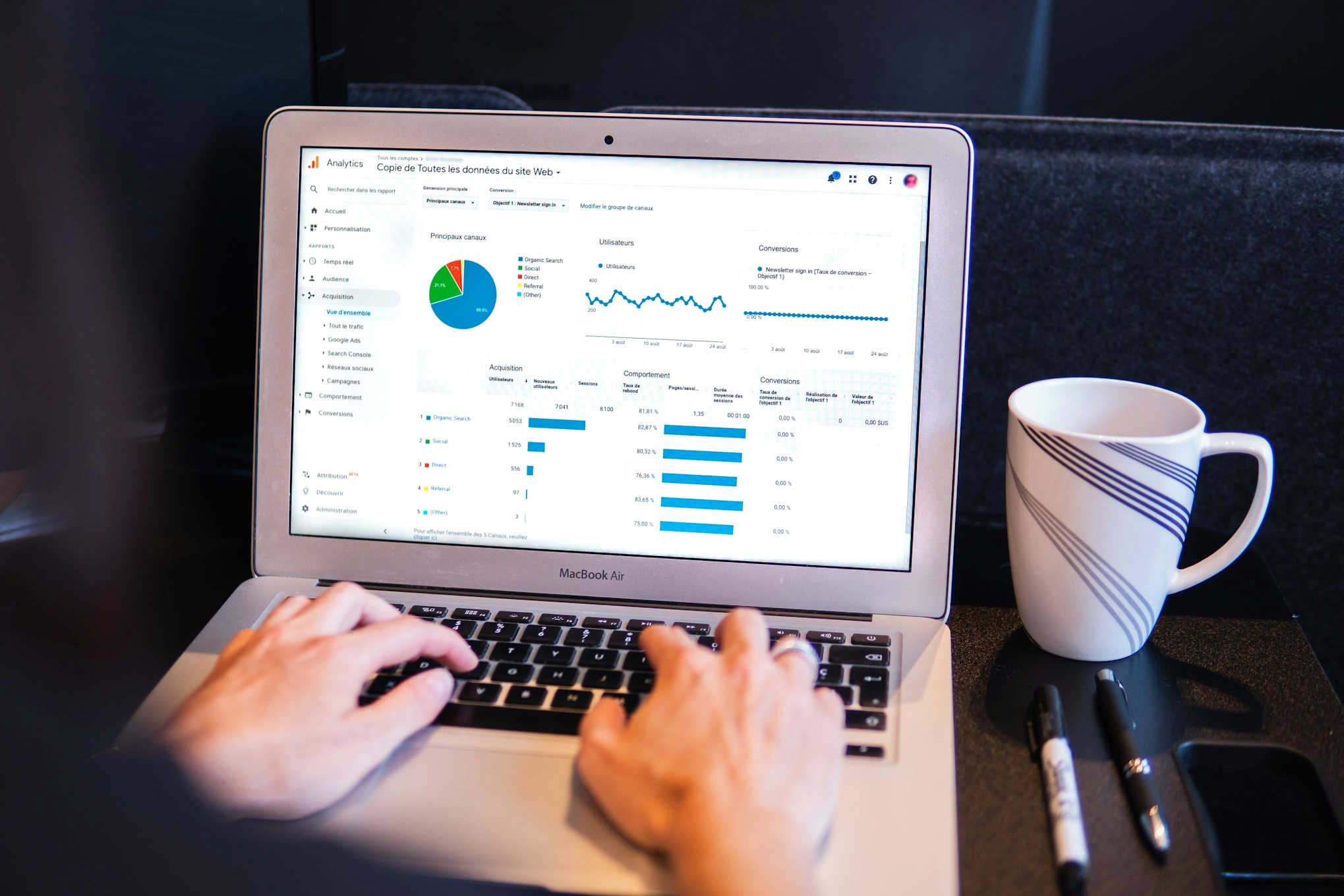 Person analysing Google Analytics data on a MacBook Air with charts and metrics on screen.