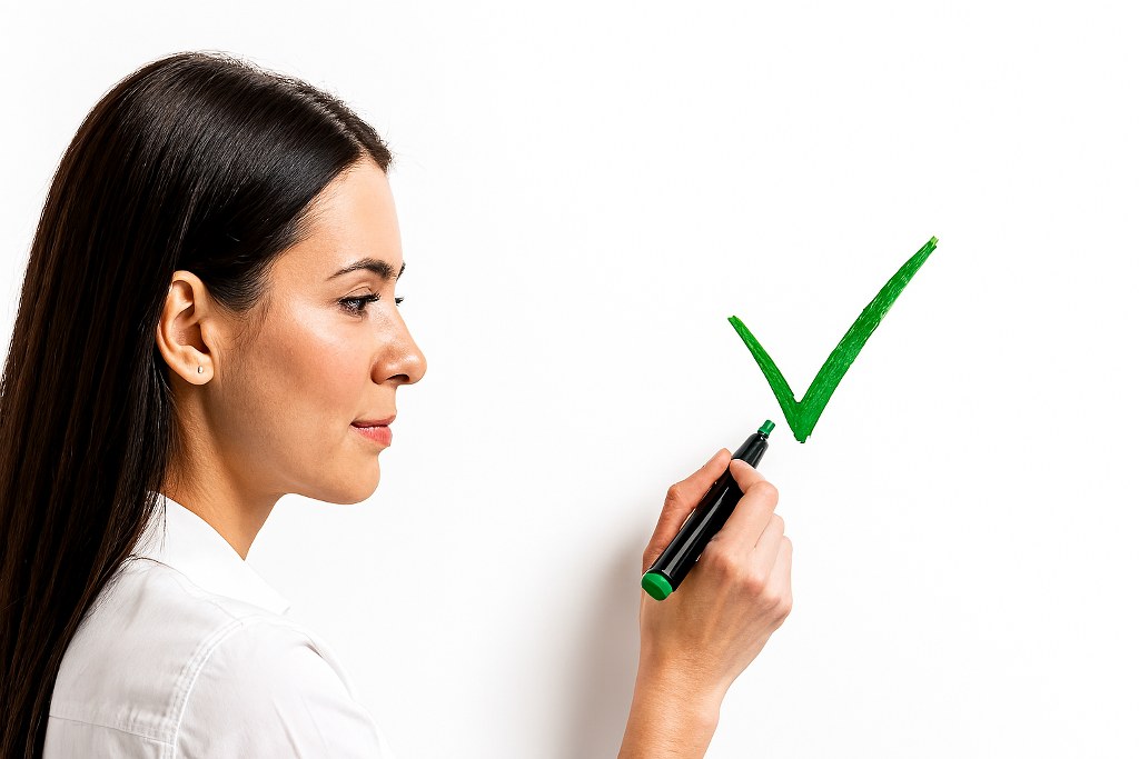A woman drawing a tick on a whiteboard.