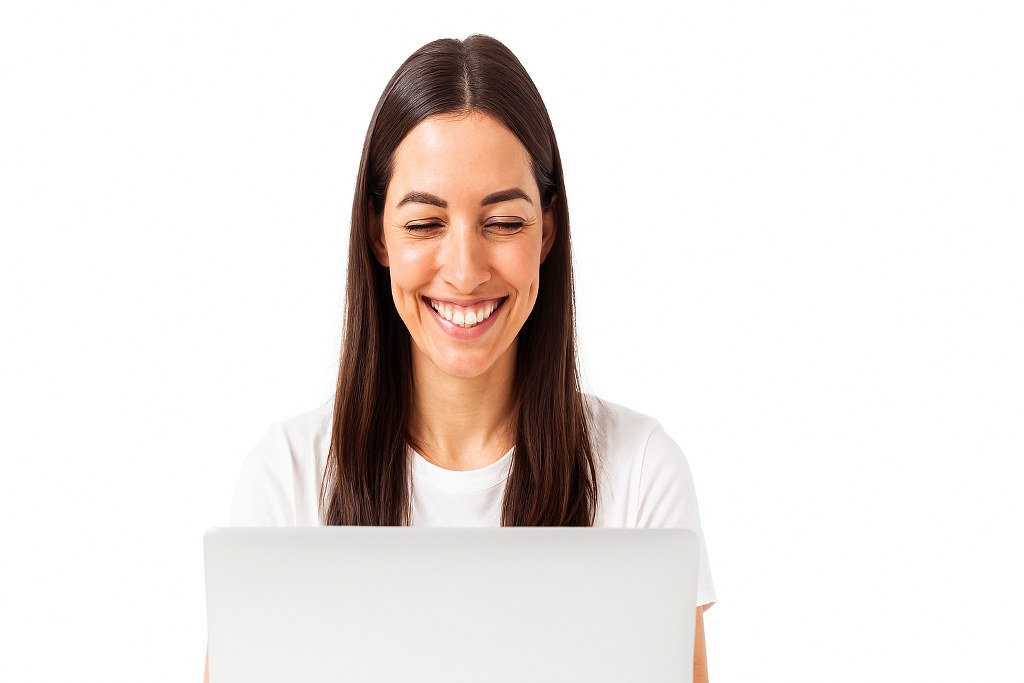 A woman smiling while looking at her laptop.