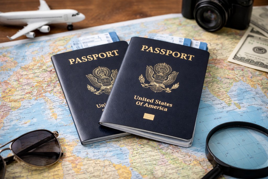 Two passports rest on a world map, surrounded by travel items
