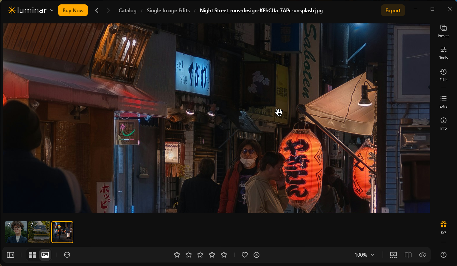 Unedited Luminar Neo night photograph at 100% zoom showing Japanese shop signs, a brightly illuminated orange lantern, pedestrians, and dark storefront details.